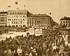 YOUNGSTORGET 1.MAI 1908:  I bakgrunnen det nye Folkets Hus. Paroler: 8 Timers Arbeidsdag - Arbeidere forener Eder - Bort med Overtidsarbeidet.