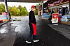 Normohammad Rezaei står på en våt Circle K-stasjon iført svart jakke, rød bukse og rød caps.